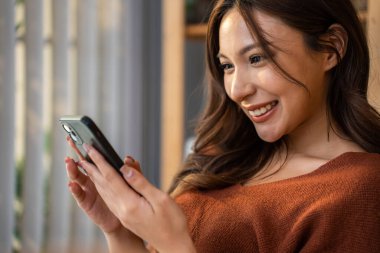 Asyalı güzel bir kadın kanepede oturuyor ve evdeki cep telefonunu çalıyor. Mutlu çekici genç kız evde vakit geçirir, rahatlar, iletişim kurar ve oturma odasında akıllı telefondan tartışır.