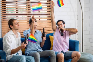 Beyaz, yakışıklı, gay bir aile, LGBTQ bayrağı taşıyor ve birlikte dans ediyorlar. Çekici genç erkek lgbt çifti müzik dinleyerek ve eğlenerek, neşeli gururla eğlenerek ve gökkuşağı bayrağı taşıyarak vakit geçirir.