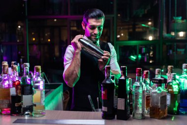 Kafkasyalı barmen bir barda kadınlara kokteyl hazırlıyor. Çekici barmen likör karışımını karıştırıyor. Kokteyl karıştırıcısından, gece kulübü restoranının bardağına..