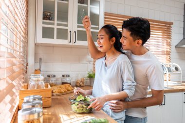 Asyalı romantik adam mutfakta kolyesiyle sürpriz sevgili yapıyor. Çekici, romantik, yeni evli çift erkek ve kadın birlikte vakit geçiriyorlar. Yıldönümünü ve sevgililer gününü evde kutluyorlar..