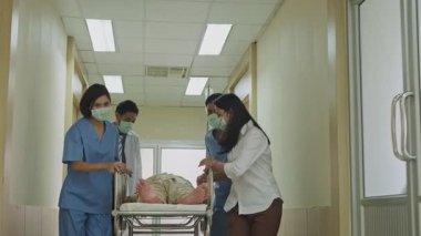 Tıbbi ekip yaşlı bir hastayı hastane koridorunda sedyeyle koşturuyor.
