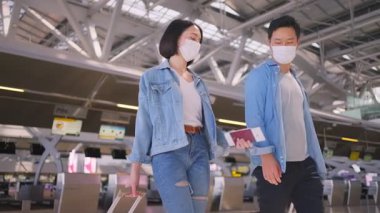 Coronavirüs enfeksiyonunu önlemek için COVID salgını sırasında havaalanı terminaline giden yüz maskesi takan erkek ve kadın yolcular.