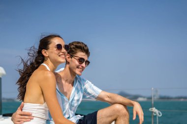 Kafkasyalı romantik çift yat gezisi sırasında güzel manzaraya bakıyor. Çekici bir genç adam ve kadın birlikte takılıp yıl dönümü balayı gezisini kutlarken katamaran teknesi yaz günbatımında yelken açıyor.