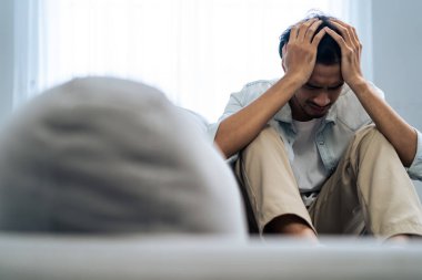 Asyalı genç üzgün bir adam evde tek başına oturuyor. Çekici mutsuz erkek çok üzgün, yalnız ve hayal kırıklığına uğramış para borçlarını, bütçe kayıplarını, iflasları düşünün..