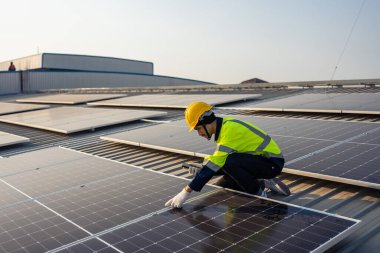 Profesyonel mühendis fotovoltaik panel sisteminin bakımı için çalışıyor. Çatı teftişi yapan çekici teknisyen güneş pili ekipman kutusunu gün batımında güneş pili alanında inceleyip kontrol ediyor.