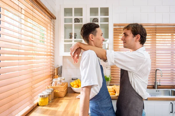 Kafkasyalı genç lgbtq gay ailesi sabah kahvaltı yapıyor. Çekici, romantik erkek çift önlük giyer. Mutfakta birlikte yemek pişirmek için mutlu ve neşeli olurlar..