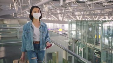 Havaalanı terminalinde yürüyen maskeli bir kadın.