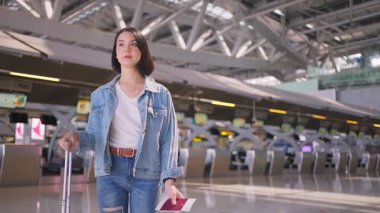 Elinde uçak bileti ve pasaportu olan güzel bir kadın havaalanı terminalinden biniş kapısına doğru yürüyor.