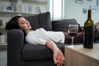 Asyalı genç bunalımlı kadın kalbi kırık ve alkol içiyor. Çekici güzel kız yalnızlık çekiyor, sarhoş ve akşamdan kalma, kanepeye uzanmış, oturma odasında bir kadeh şarap tutuyor..