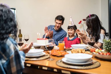 Çok ırklı büyük bir aile, küçük kız çocukları için doğum günü partisi veriyor. Çok hoş bir çeşitlilik anı. İnsanlar küçük kız çocuğuna doğum günü şarkısı söylüyor. Sonra da yemek masasında pastaya mum üflüyor.