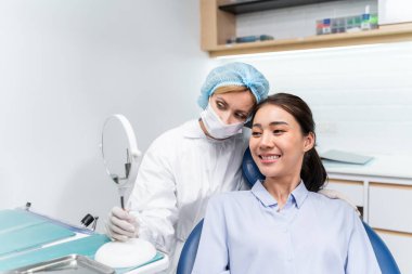 Beyaz dişçi diş sağlığı kliniğindeki genç kız için dişleri muayene ediyor. Diş hekimliği koltuğunda yatan çekici kadın hastanede muayene sırasında doktordan diş tedavisi görüyor.