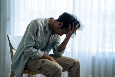 Asyalı genç üzgün bir adam evde tek başına oturuyor. Çekici mutsuz erkek çok üzgün, yalnız ve hayal kırıklığına uğramış para borçlarını, bütçe kayıplarını, iflasları düşünün..