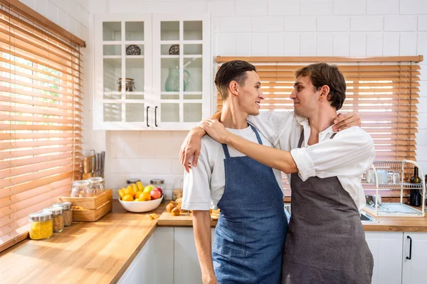 Kafkasyalı genç lgbtq eşcinsel ailesi sabahları evde yemek pişiriyor. Çekici, romantik erkek çift önlük giyer. Mutfakta birlikte kahvaltı yaparken mutlu ve neşeli olurlar.