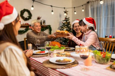 Asyalı aile Noel partisinde küçük kızına hediye paketi veriyor. Çekici küçük kız, yemek yerken akrabalarından hediyeler alır Şükran Günü 'nü birlikte yemek masasında kutlarız.