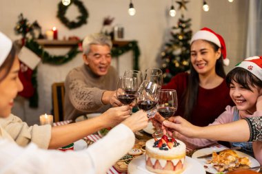 Asyalı aile Noel partisinde küçük kızına hediye paketi veriyor. Çekici küçük kız, yemek yerken akrabalarından hediyeler alır Şükran Günü 'nü birlikte yemek masasında kutlarız.