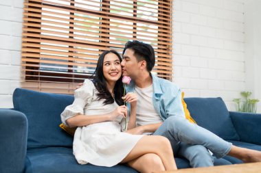 Asyalı genç adam sürpriz yaptı ve gül çiçeğini güzel kız arkadaşına verdi. Çekici, romantik, yeni evli çift erkek ve kadın yıl dönümünü ve Sevgililer Günü 'nü kutlamak için birlikte evde vakit geçirirler..