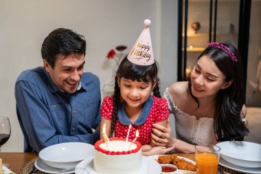 Çok ırklı büyük bir aile, küçük kız çocukları için doğum günü partisi veriyor. Çok hoş bir çeşitlilik anı. İnsanlar küçük kız çocuğuna doğum günü şarkısı söylüyor. Sonra da yemek masasında pastaya mum üflüyor.