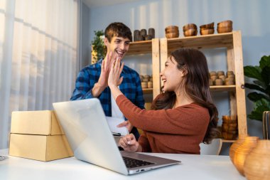 Çekici genç çift vazo siparişini müşteri için kutuya koyuyor. Çalışan işadamı ve kadın paket kutuları hazırlamak için çalışıyor. Ev mağazasında satmak üzere çevrimiçi ticaret perakendecilerini kontrol ediyorlar.