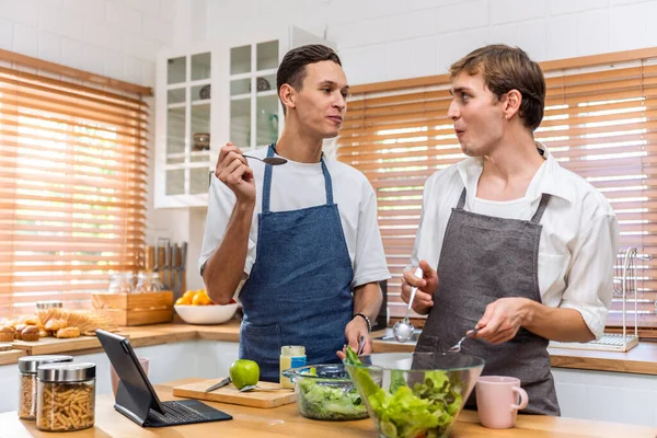 Kafkasyalı genç lgbtq eşcinsel ailesi sabahları evde yemek pişiriyor. Çekici, romantik erkek çift önlük giyer. Mutfakta birlikte kahvaltı yaparken mutlu ve neşeli olurlar.