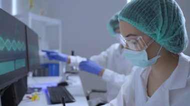 Asyalı erkek ve kadın bilim adamları araştırma laboratuvarında birlikte çalışıyorlar..