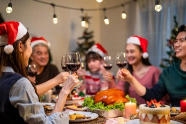 Asyalı sevimli aile Noel partisini evde kutluyor. Çekici ebeveynler ve akrabalar yemek yiyor, Şükran Günü 'nü kutlamak için bir kadeh şarap içiyorlar, yemek masasında Noel arifesi.