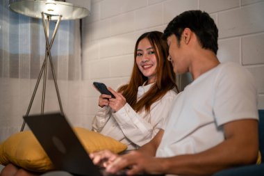 Asyalı genç adam geceleri karısıyla birlikte dizüstü bilgisayarda çalışıyor. Pijamalı çekici bir kız arkadaş akıllı telefon kullanıyor. Bekleyen koca evde yatmadan önce bilgisayarla iletişim kuruyor.