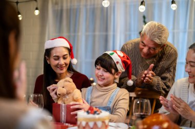 Asyalı aile Noel partisinde küçük kızına hediye paketi veriyor. Çekici küçük kız, yemek yerken akrabalarından hediyeler alır Şükran Günü 'nü birlikte yemek masasında kutlarız.