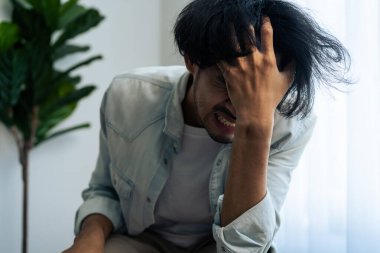 Asyalı genç üzgün bir adam evde tek başına oturuyor. Çekici mutsuz erkek çok üzgün, yalnız ve hayal kırıklığına uğramış para borçlarını, bütçe kayıplarını, iflasları düşünün..