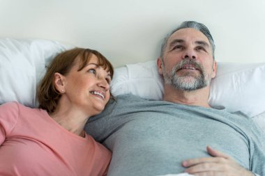 Kafkasyalı yaşlı çift yatağa uzanıp birbirlerine bakıyorlar. Çekici, yaşlı, pijamalı kadın ve erkek evdeki yatak odasında sabahın erken saatlerinde eğleniyorlar. Aile ilişkisi kavramı