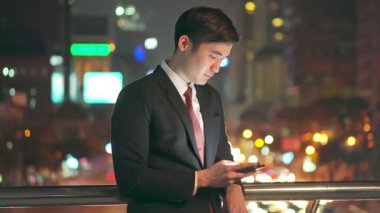 Asyalı işadamı, acil bir işi tamamlamak için gece iş arkadaşlarıyla telefonda çene çalarak çalışıyor. Akıllı işçi arkadaşlarıyla internetle iletişim kurarken mutlu ve gülümser..