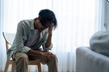 Asyalı genç üzgün bir adam evde tek başına oturuyor. Çekici mutsuz erkek çok üzgün, yalnız ve hayal kırıklığına uğramış para borçlarını, bütçe kayıplarını, iflasları düşünün..