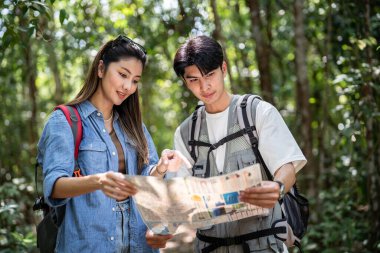 Asyalı genç adam ve kadın sırt çantalı turist orman vahşiliğinde seyahat ediyorlar. Çekici bir çift gezgini, tatil gezisi sırasında doğa ormanında mutluluk ve eğlenceyle dolaşırken etrafa bakar ve keşfe çıkar..