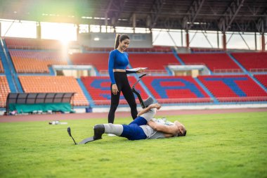 Protez bıçaklı Asyalı bir sporcu ve stadyumda antrenman yapıyor. Çekici ampüte erkek koşucu ve genç sporcu mutlu ve Engelliler Koşu Yarışması 'nda antrenman yapmaktan zevk alıyor..
