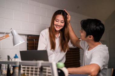 Asyalı genç adam gece evde karısıyla birlikte yatak odasında çok çalışıyor. Pijamalı çekici bir eş kocasını bekliyor dizüstü bilgisayarını kullanıyor yatmadan önce internette iletişim kuruyor..
