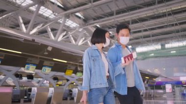 Coronavirüs enfeksiyonunu önlemek için COVID salgını sırasında havaalanı terminaline giden yüz maskesi takan erkek ve kadın yolcular.