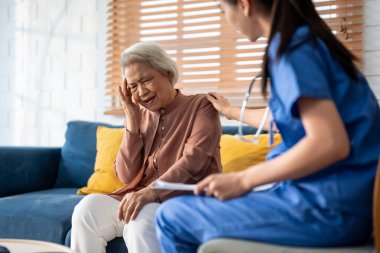 Asyalı genç bakıcı hemşire evdeki yaşlı kadın hastayı muayene ediyor. Çekici uzman bakıcı kadınlar destek oluyor, yaşlı olgun büyükannelere danışmanlık yapıyor ve danışmanlık yapıyorlar..