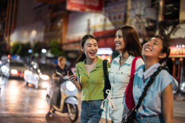 Asyalı güzel bayan arkadaş geceleyin şehir dışında geziyor. Çekici kızlar mutlu ve rahat hissediyorlar, sokaklarda yürüyüp tatil için boş vakitlerini birlikte geçiriyorlar..