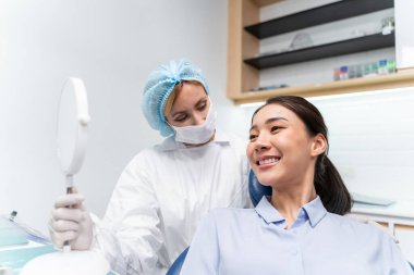 Beyaz dişçi diş sağlığı kliniğindeki genç kız için dişleri muayene ediyor. Diş hekimliği koltuğunda yatan çekici kadın hastanede muayene sırasında doktordan diş tedavisi görüyor.