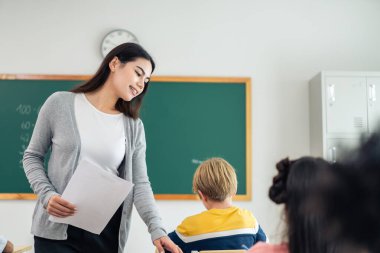 İlkokulda sınıf öğretmeniyle sevimli bir öğrenci öğreniyor. Çekici, güzel bayan eğitmen. Sınav kağıdını küçük çocuklara geçer. Anaokulunda mutlu bir şekilde masaya otururlar..