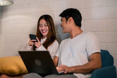 Asyalı genç adam geceleri karısıyla birlikte dizüstü bilgisayarda çalışıyor. Pijamalı çekici bir kız arkadaş akıllı telefon kullanıyor. Bekleyen koca evde yatmadan önce bilgisayarla iletişim kuruyor.