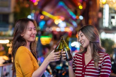 Asyalı kadın arkadaşlar ellerinde bira şişesi, barın önünde parti veriyorlar. İki güzel bayan gezgin şehir dışına seyahat ediyor, gece kulübünde tatil gezisinde kutlama yaparak vakit geçiriyorlar..