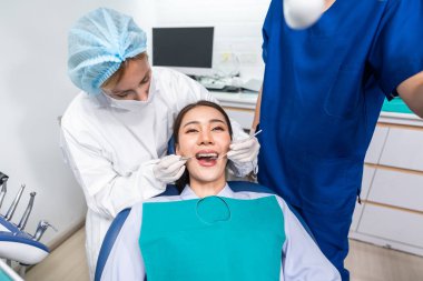 Beyaz dişçi diş sağlığı kliniğindeki genç kız için dişleri muayene ediyor. Diş hekimliği koltuğunda yatan çekici kadın hastanede muayene sırasında doktordan diş tedavisi görüyor.