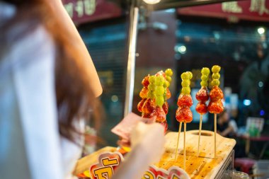 Geceleri şehir dışına çıkan güzel bir kadına yakın durun. Çekici kız turist kendini mutlu ve rahat hissediyor, yürüyor ve sokak yemekleri alıyor tatil için boş zaman harcıyor..