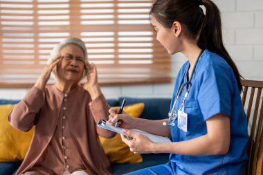 Asyalı genç bakıcı hemşire evdeki yaşlı kadın hastayı muayene ediyor. Çekici uzman bakıcı kadınlar destek oluyor, yaşlı olgun büyükannelere danışmanlık yapıyor ve danışmanlık yapıyorlar..