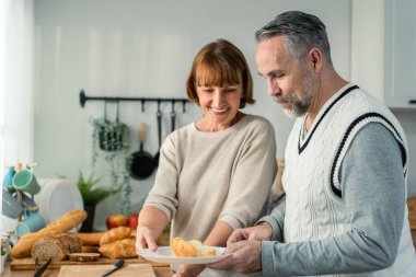Kafkasyalı yaşlı çift evde mutfakta birlikte vakit geçiriyorlar. Çekici, olgun bir erkek ve kadın kahvaltıda yemek pişiriyor ve evde mutluluk var. Aile ilişkileri aktivite kavramı.