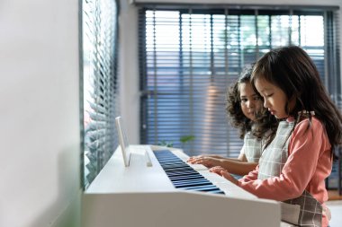 İki Asyalı sevimli kardeş evdeki oturma odasında piyano çalıyorlar. Mutlu Aile, küçük kız çocukları mutlu ve rahat hissederken boş zamanlarını evdeki müzik sınıfında öğrenerek geçiriyorlar..