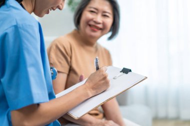 Asyalı genç bakıcı hemşire evdeki yaşlı kadın hastayı muayene ediyor. Çekici uzman bakıcı kadınlar destek oluyor, yaşlı olgun büyükannelere danışmanlık yapıyor ve danışmanlık yapıyorlar..