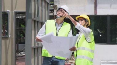 Mimarlık alanında koruyucu kasklar takan Asyalı iş arkadaşları