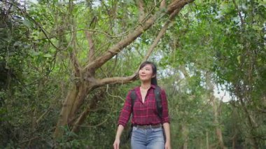 Asyalı genç kadın yeşil orman yolunda yürüyor..