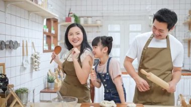 Genç Asyalı aile mutfakta yemek pişirirken dans ediyor.